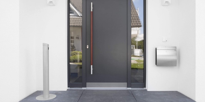 Moderne Hauseingangstür in Anthrazit mit seitlichen Glaselementen, Edelstahlbriefkasten und stilvollem Türgriff aus Holz und Metall.